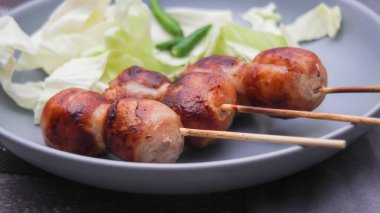 Izgara mayalanmış domuz eti ve gri tabakta yapışkan pirinç sosisi..