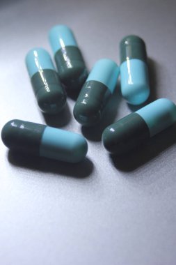 Mavi-yeşil hap kapsülleri gümüş bir masaya yerleştirildi..