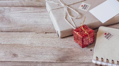 Hediye kutusu Tahta bir masa üzerinde kahverengi geri dönüşümlü kağıt ve not defteri kullanın.