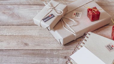 Hediye kutusu Tahta bir masa üzerinde kahverengi geri dönüşümlü kağıt ve not defteri kullanın.