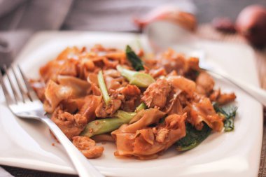 Beyaz tabakta servis edilen Tayland Soya Sosu Kızarmış Eriştesi. Siyah tahta masada ya da 