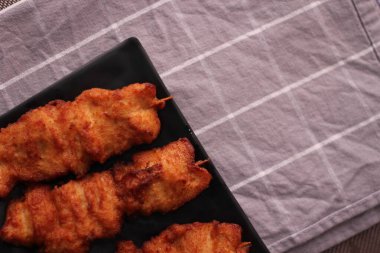 Siyah tabakta servis edilen kızarmış domuz şişleri..