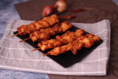 Siyah tabakta servis edilen kızarmış domuz şişleri..