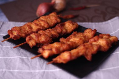 Siyah tabakta servis edilen kızarmış domuz şişleri..