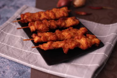 Siyah tabakta servis edilen kızarmış domuz şişleri..