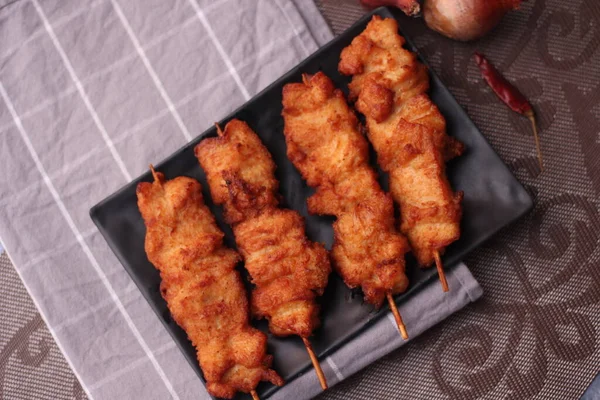 Siyah tabakta servis edilen kızarmış domuz şişleri..