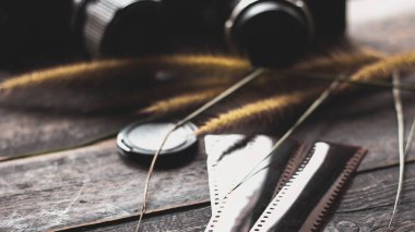 Retro film kamerası ve negatif film siyah ahşap bir masada.