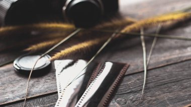 Retro film kamerası ve negatif film siyah ahşap bir masada.