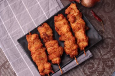 Siyah tabakta servis edilen kızarmış domuz şişleri..