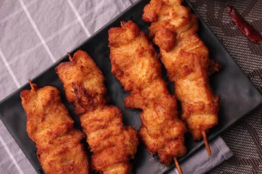 Siyah tabakta servis edilen kızarmış domuz şişleri..