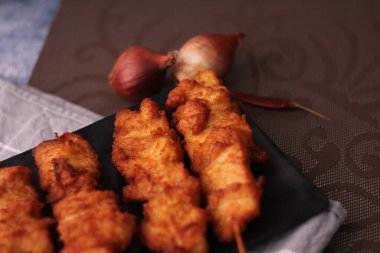 Siyah tabakta servis edilen kızarmış domuz şişleri..