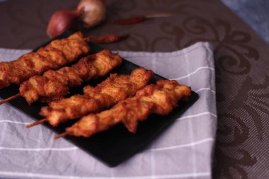 Siyah tabakta servis edilen kızarmış domuz şişleri..