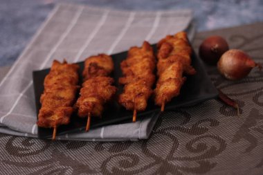 Siyah tabakta servis edilen kızarmış domuz şişleri..