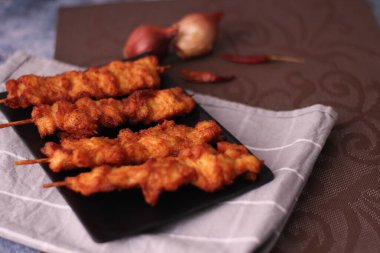 Siyah tabakta servis edilen kızarmış domuz şişleri..