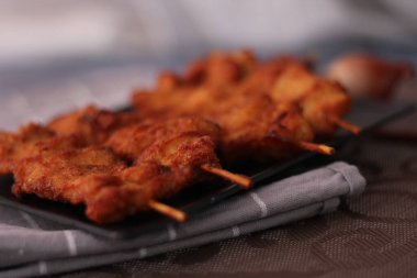 Siyah tabakta servis edilen kızarmış domuz şişleri..