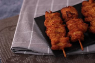 Siyah tabakta servis edilen kızarmış domuz şişleri..