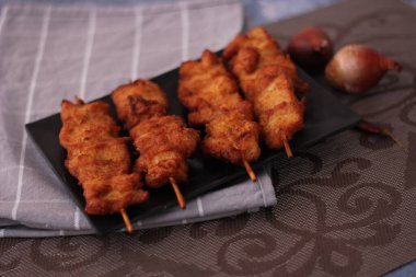 Siyah tabakta servis edilen kızarmış domuz şişleri..