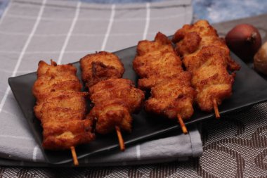 Siyah tabakta servis edilen kızarmış domuz şişleri..