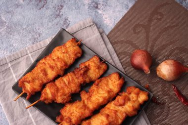 Siyah tabakta servis edilen kızarmış domuz şişleri..