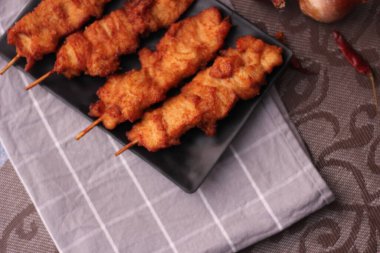 Siyah tabakta servis edilen kızarmış domuz şişleri..