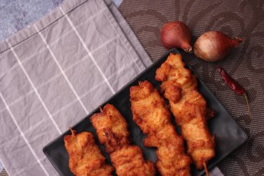 Siyah tabakta servis edilen kızarmış domuz şişleri..