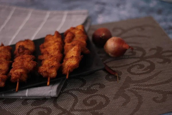 Siyah tabakta servis edilen kızarmış domuz şişleri..