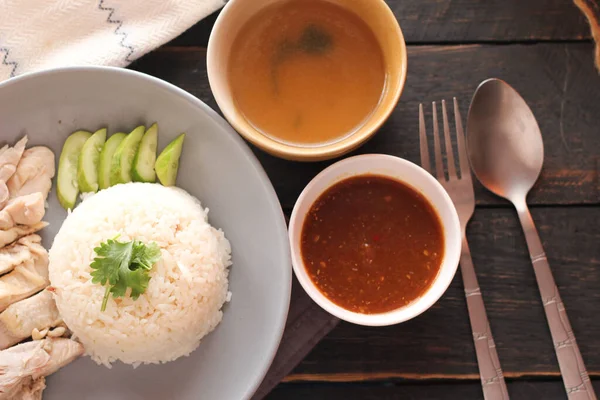 黒木のテーブルの上に醤油と熱いスープを添えた海南鶏飯 — ストック写真
