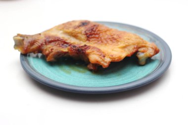 Beyaz bir masada servis edilen yeşil tabakta ızgara tavuk..