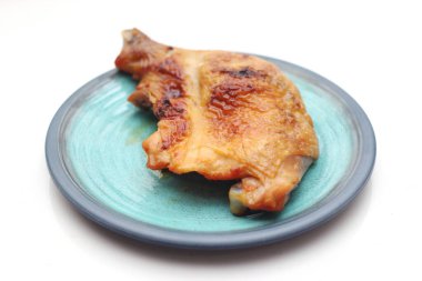 Beyaz bir masada servis edilen yeşil tabakta ızgara tavuk..