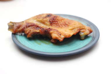 Beyaz bir masada servis edilen yeşil tabakta ızgara tavuk..