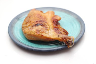 Beyaz bir masada servis edilen yeşil tabakta ızgara tavuk..