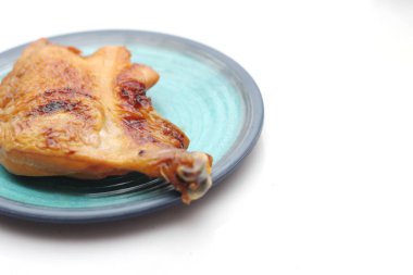 Beyaz bir masada servis edilen yeşil tabakta ızgara tavuk..