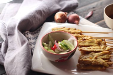 Fıstık ve salatalık soslu, beyaz bir tabakta servis edilen domuz eti..