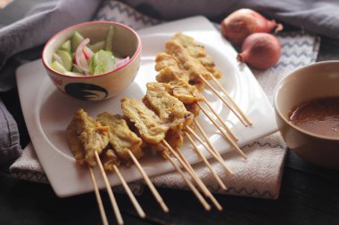 Fıstık ve salatalık soslu, beyaz bir tabakta servis edilen domuz eti..