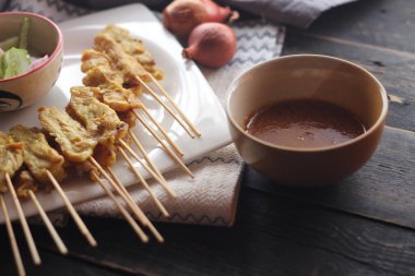 Fıstık ve salatalık soslu, beyaz bir tabakta servis edilen domuz eti..