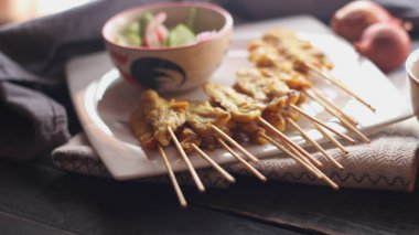 Fıstık ve salatalık soslu, beyaz bir tabakta servis edilen domuz eti..