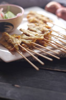 Fıstık ve salatalık soslu, beyaz bir tabakta servis edilen domuz eti..