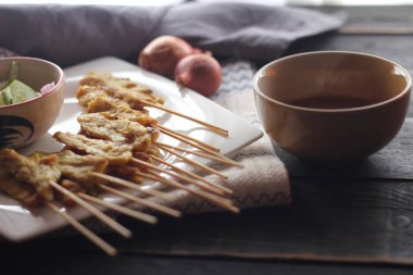 Fıstık ve salatalık soslu, beyaz bir tabakta servis edilen domuz eti..