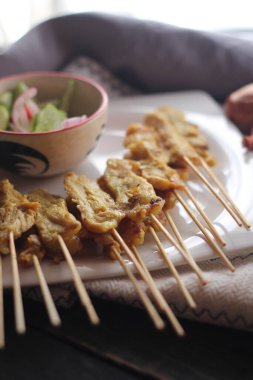 Fıstık ve salatalık soslu, beyaz bir tabakta servis edilen domuz eti..