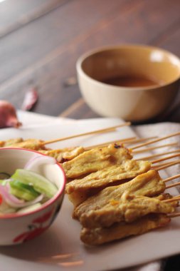 Fıstık ve salatalık soslu, beyaz bir tabakta servis edilen domuz eti..