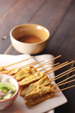 Fıstık ve salatalık soslu, beyaz bir tabakta servis edilen domuz eti..