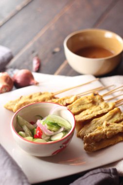 Fıstık ve salatalık soslu, beyaz bir tabakta servis edilen domuz eti..