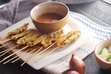 Fıstık ve salatalık soslu, beyaz bir tabakta servis edilen domuz eti..