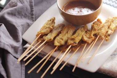 Fıstık ve salatalık soslu, beyaz bir tabakta servis edilen domuz eti..