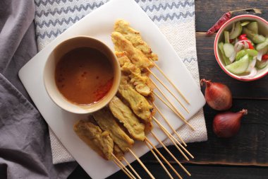 Fıstık ve salatalık soslu, beyaz bir tabakta servis edilen domuz eti..