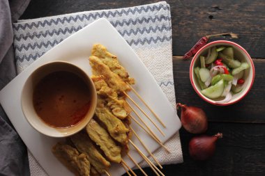 Fıstık ve salatalık soslu, beyaz bir tabakta servis edilen domuz eti..