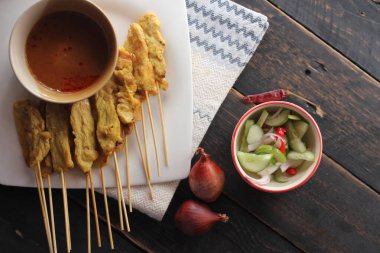 Fıstık ve salatalık soslu, beyaz bir tabakta servis edilen domuz eti..