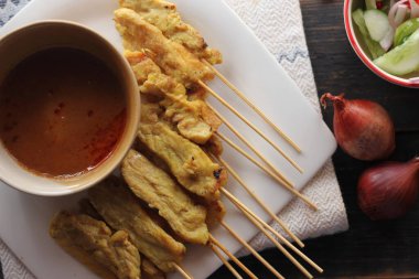 Fıstık ve salatalık soslu, beyaz bir tabakta servis edilen domuz eti..