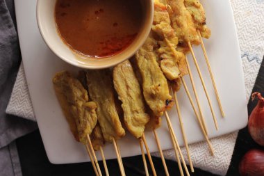 Fıstık ve salatalık soslu, beyaz bir tabakta servis edilen domuz eti..