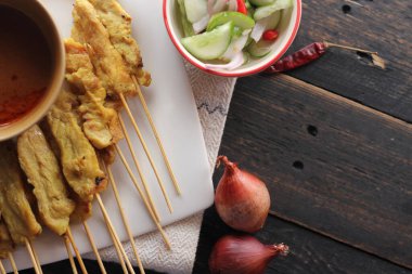 Fıstık ve salatalık soslu, beyaz bir tabakta servis edilen domuz eti..